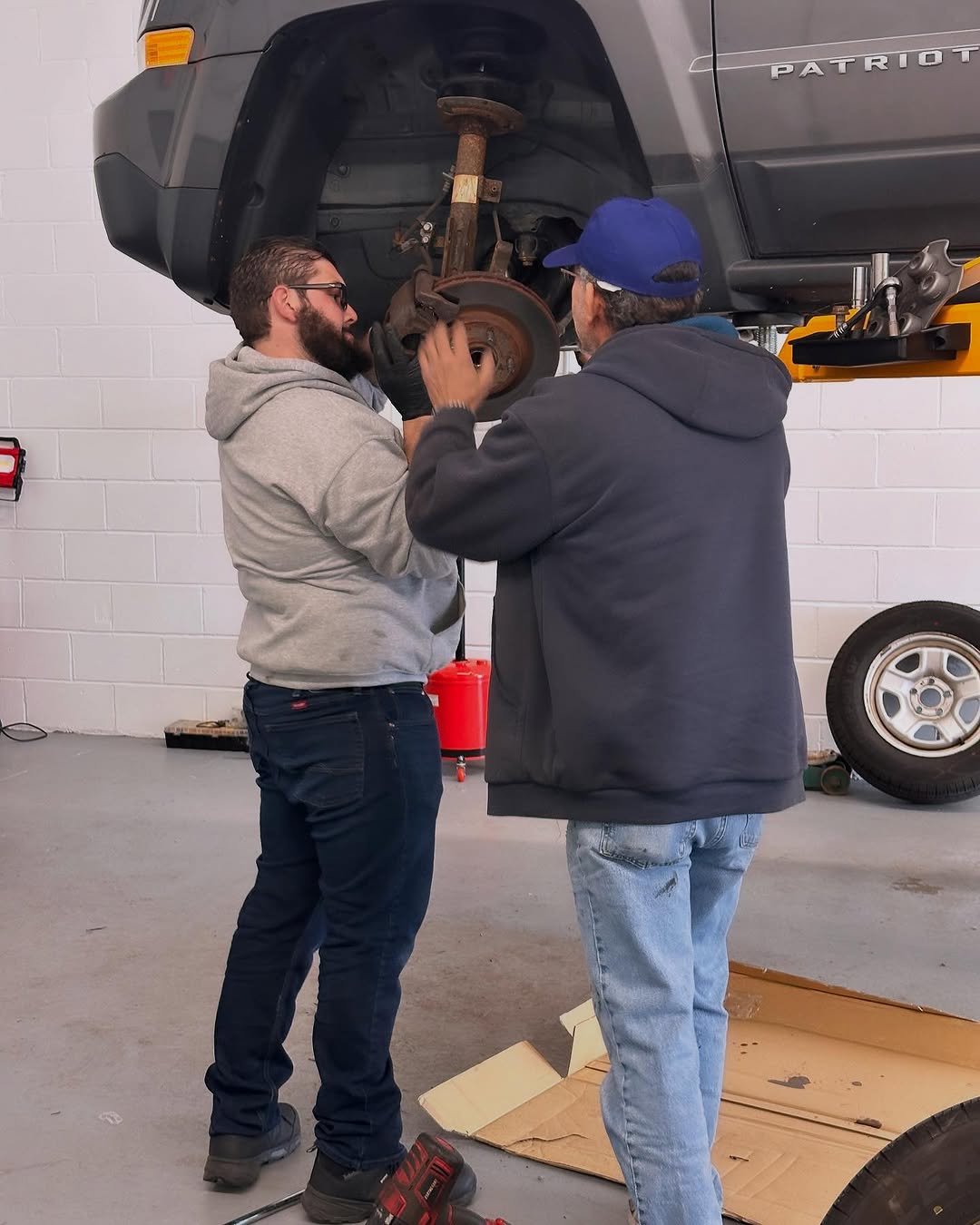 David working with another technician on a raised vehicle at Mr. Honditas in Toms River, NJ