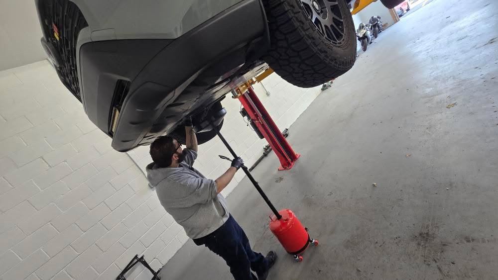 Oil change service being completed on a raised vehicle at Mr. Honditas in Toms River, NJ